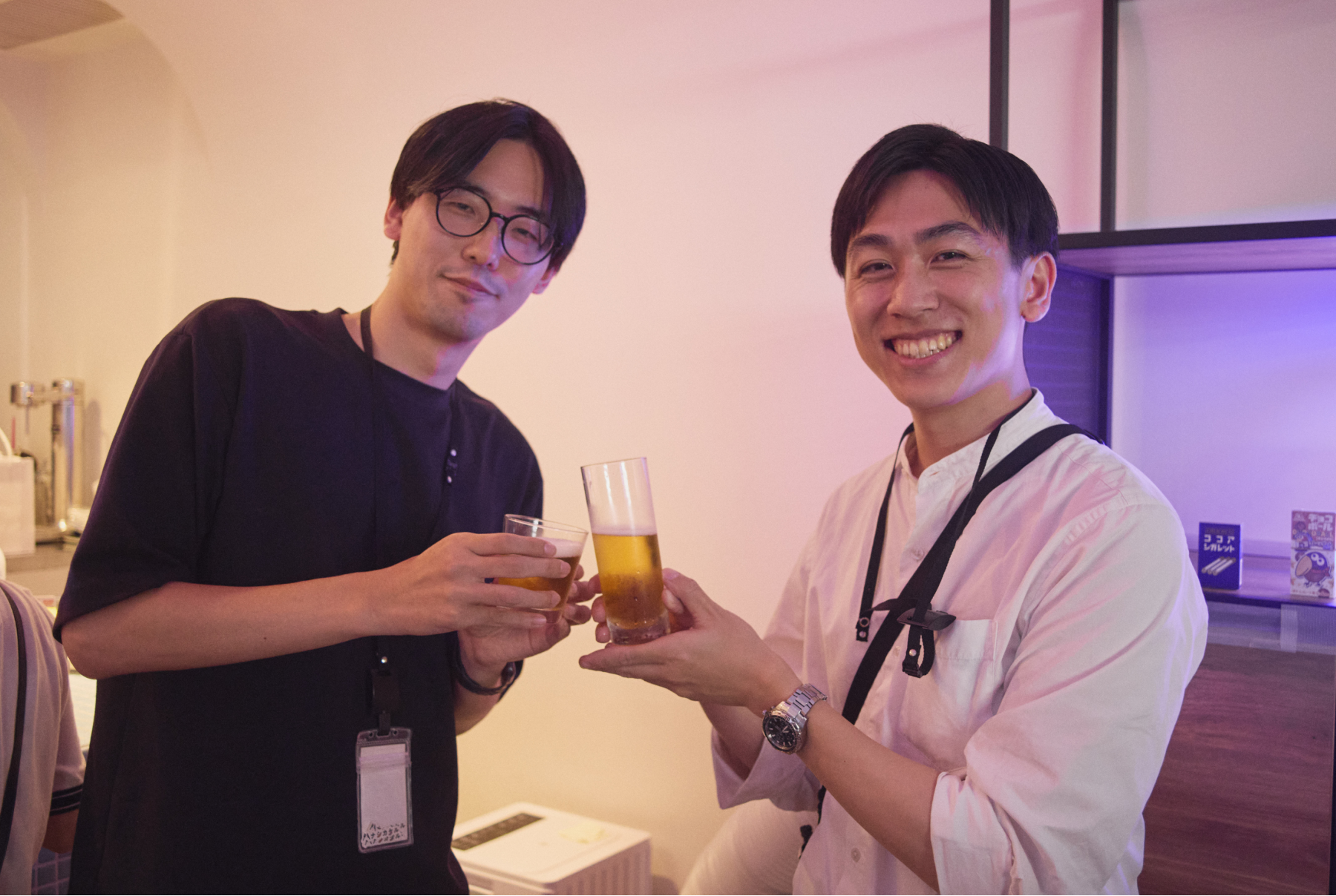 社内Barで笑顔の男性社員二人が乾杯している様子