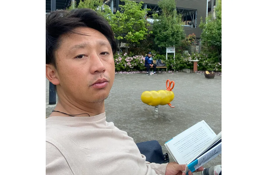 近所の公園で参考図書を読む様子。家の中では、落ち着いて読めない本を近所の公園で読む