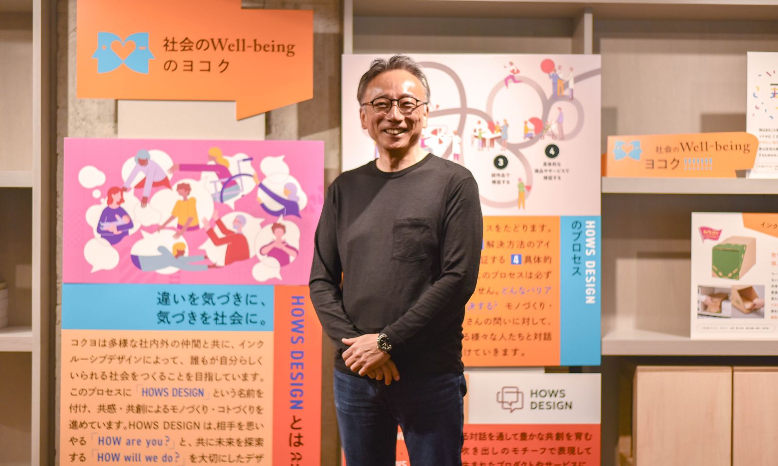 ハウズデザインについて紹介しているパネルの前で、井田さんが立って微笑んでいる