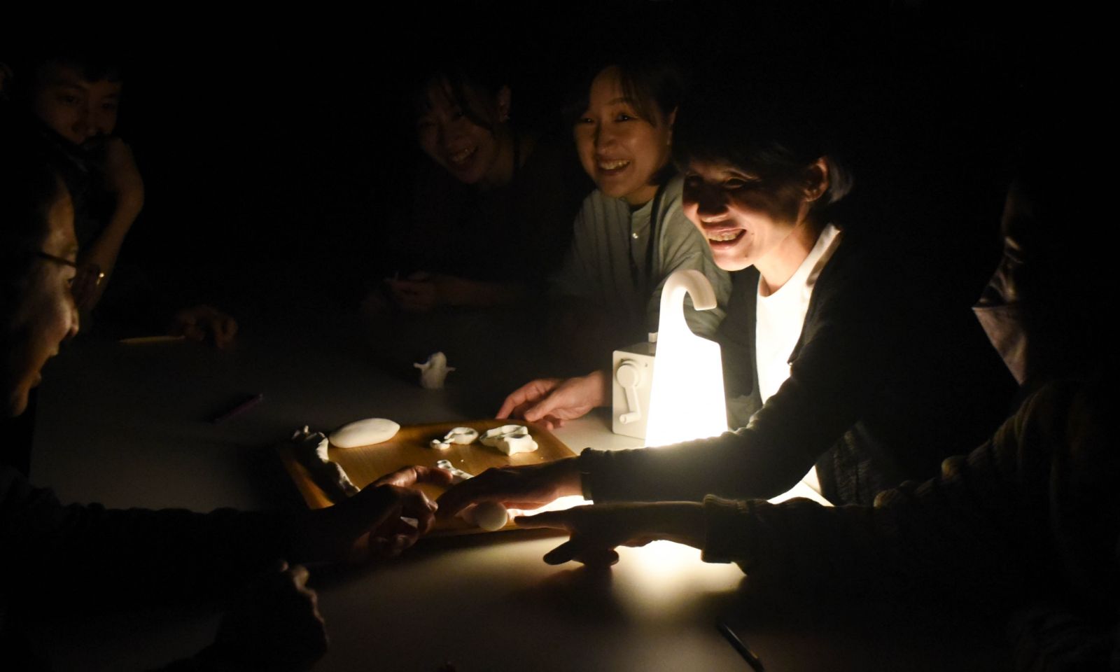 暗闇の中でつくった粘土の作品を、スタンドライトの薄明るい光のなかでアテンダーが触れている