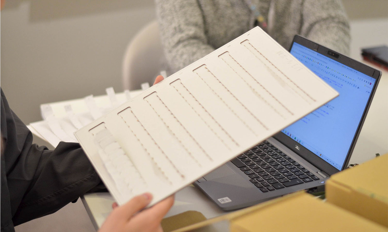 ワークショップで利用した、何種類もの開け口の切り取りジッパーを手に説明する様子