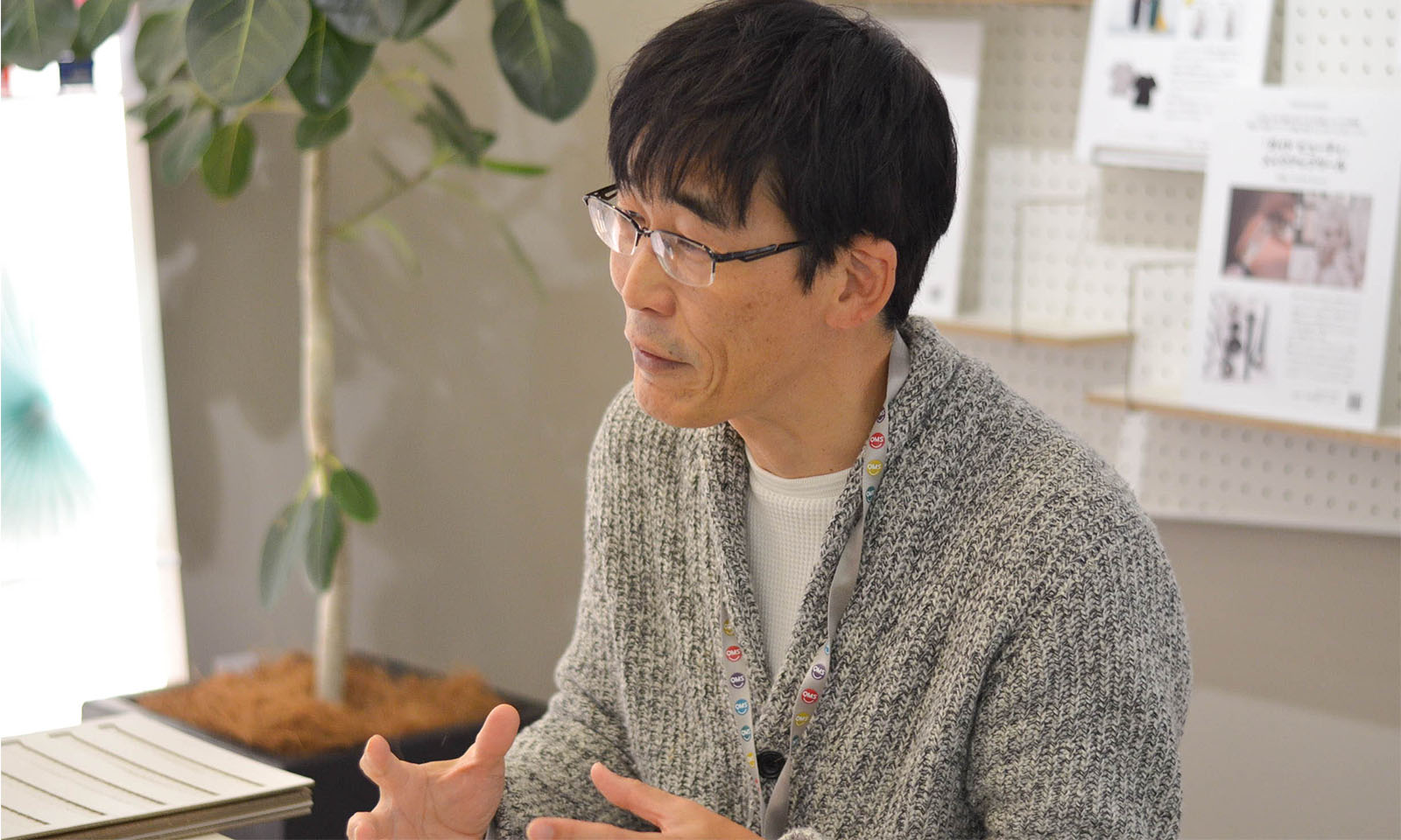 インタビューに笑顔で答えるグレーのセーターを着た、カウネット商品企画担当の青井さん