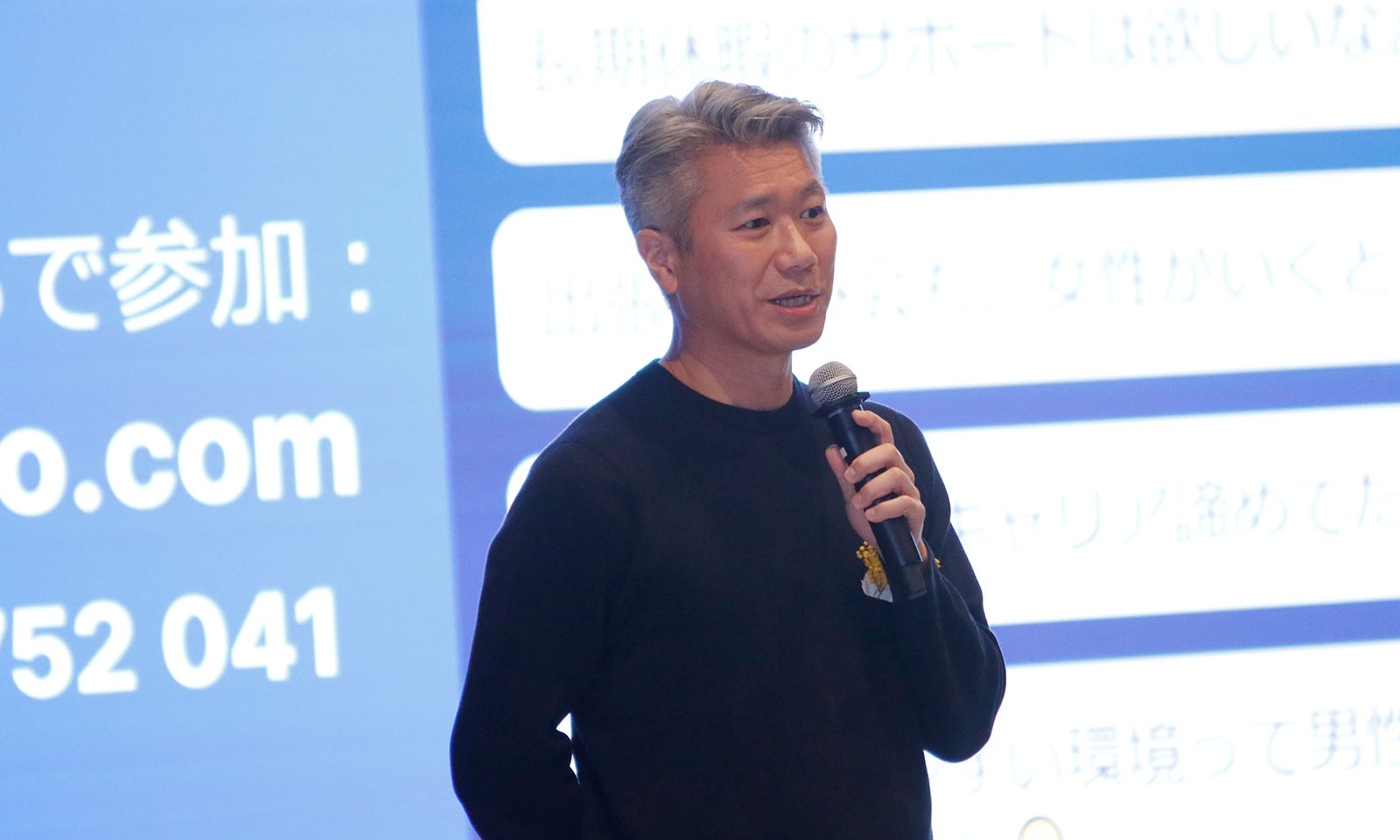 ステージ前方に立ちマイクを持ちながら話す越川さん