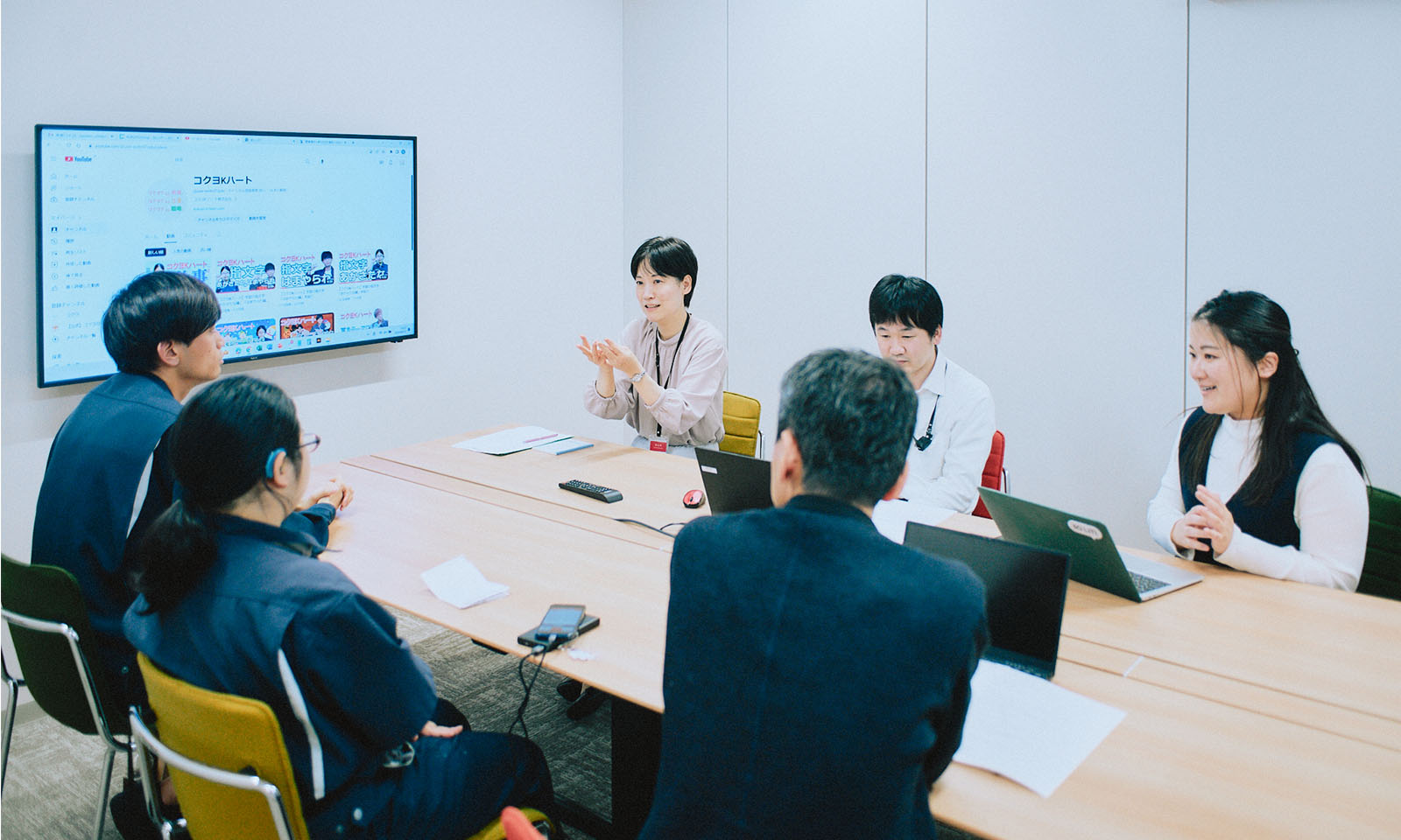 今回の取材の様子。大きなテーブルを手話通訳の大伴さん、インタビュアーの田中さんも入って囲み、画面でYouTubeチャンネルや社内用の動画を見ながら、インタビューを進めた