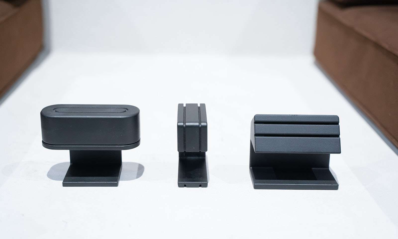 ALTはじまり。これまで試しに作ってきたコンセントのサンプル。陸上のトラックのように長い円のように挿し口があるものもあれば、真上から差すタイプ、そして今回起用された斜めから指すタイプなど色々。白い背景に黒い３つのサンプルが置かれている。ALTおわり。