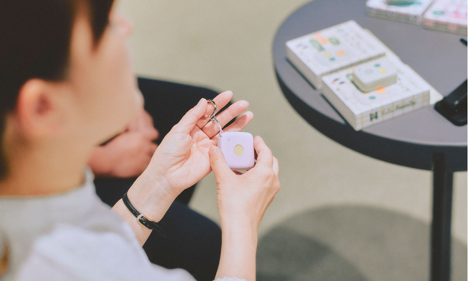 <ALT始まり>話題に出た旧タイプの製品のアップ。キーホルダーのチェーンがついた手のひらサイズの四角いボディには、真ん中にひとつだけ押しボタンがついている。<ALT終わり>