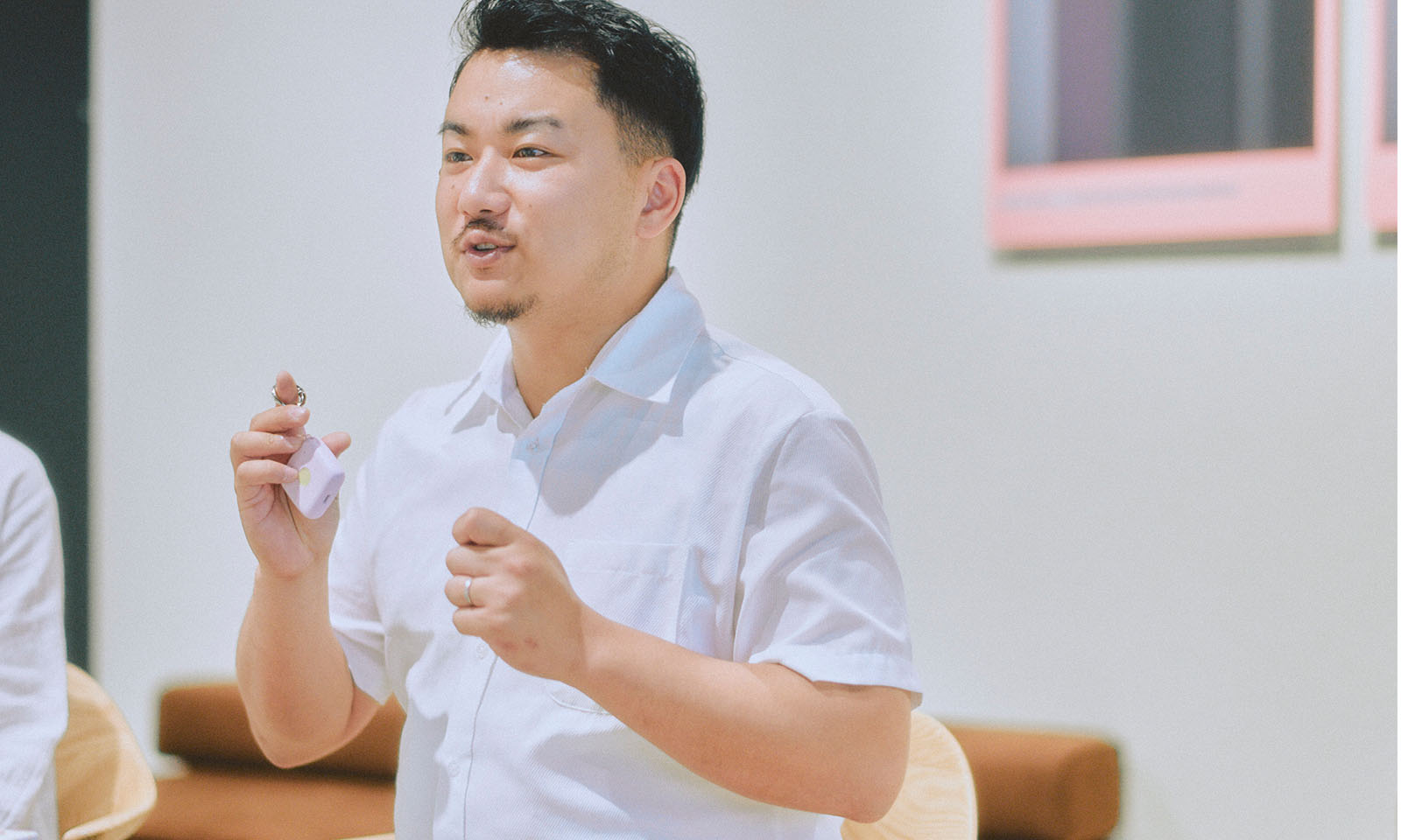 <ALT始まり>インタビューに答える中筋さんの様子。旧タイプの製品を手にしながら、身振り手振りを加えつつリラックスした様子で話されている。<ALT終わり>