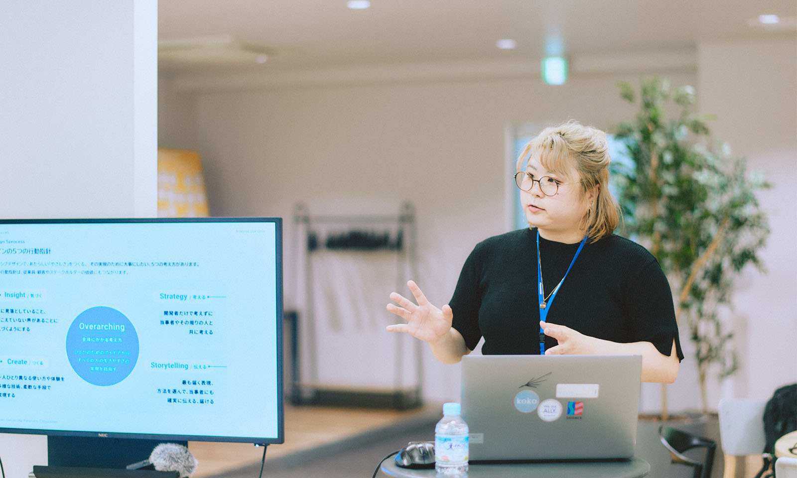 ALTはじまり。金髪でボブヘアー、まる眼鏡をかけ、黒いTシャツを着るパナソニックの白鳥さん。スクリーンに映し出されたパナソニックが大切にしている５つのことを説明している様子。ALTおわり。
