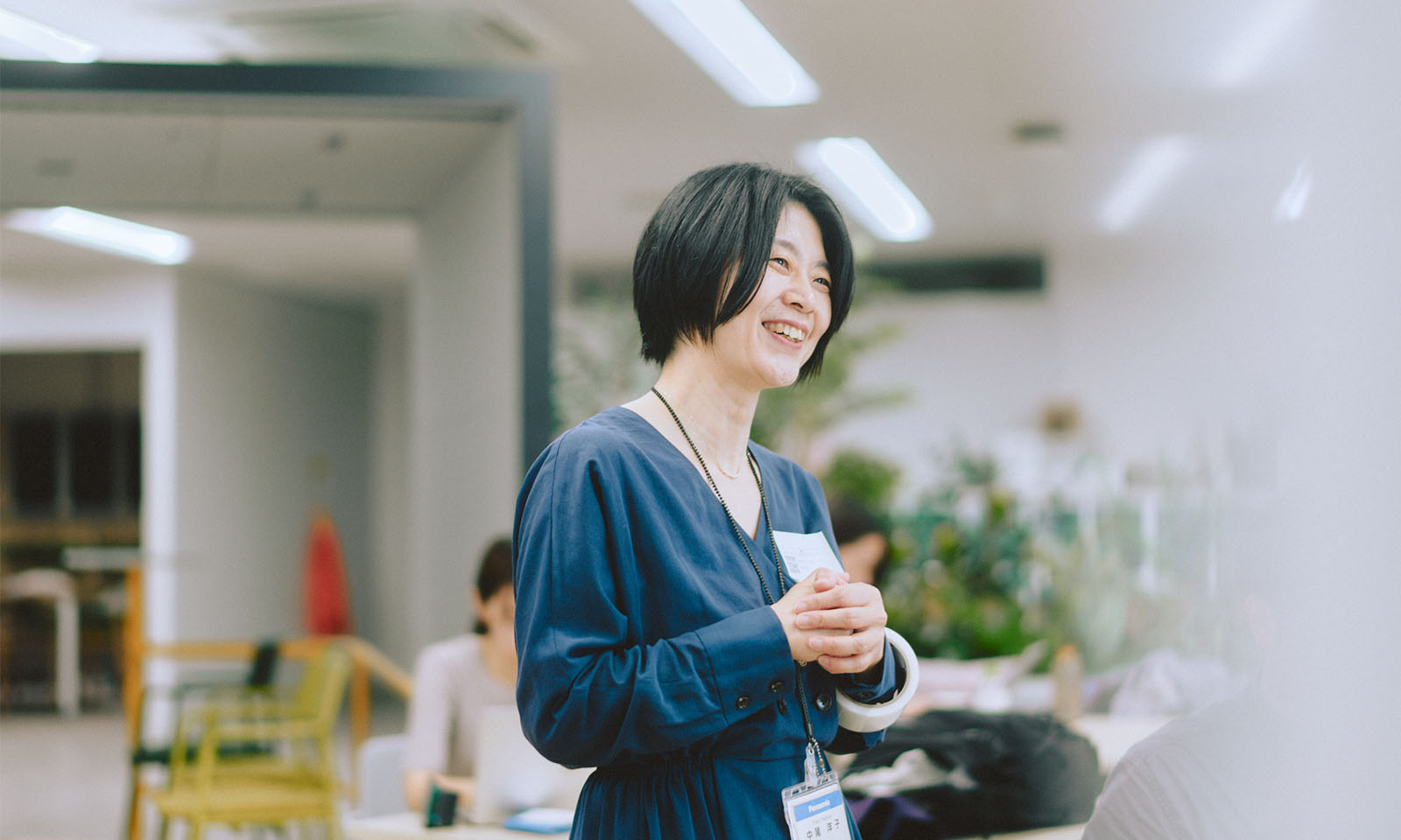 ALTはじまり。黒髪でショートヘアー、ネイビーのワンピースを着ているパナソニックの中尾さん。左胸に名前を書いた名刺サイズのステッカーをはっている。ALTおわり。