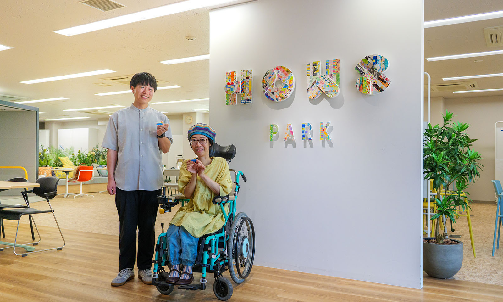 <ALT始まり>「HOWS PARK」のロゴの前で撮影したインタビュイーの二人。この「HOWS PARK」もHOWS DESIGNの考え方をもとに構築している。<ALT終わり>