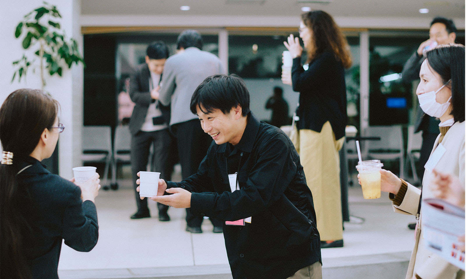 （ALT始まり）紙コップを片手に乾杯をする参加者たち。表情は柔らかい。（ALT終わり）