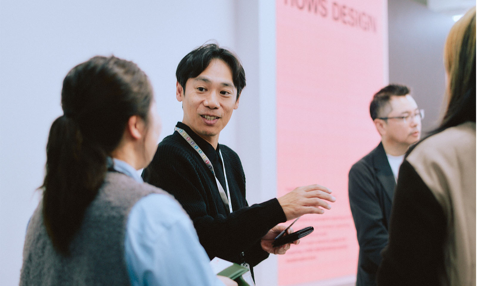 （ALT始まり）名刺交換をしながら会話する参加者の様子。落ち着きのある楽しげな表情で、手振りを加えて話をしている。（ALT終わり）