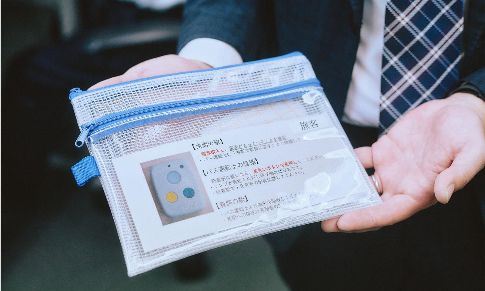 （ALT始まり）ビニールポーチの表にGPS端末はろここトークの操作方法を書いた紙が貼られている様子（ALT終わり）