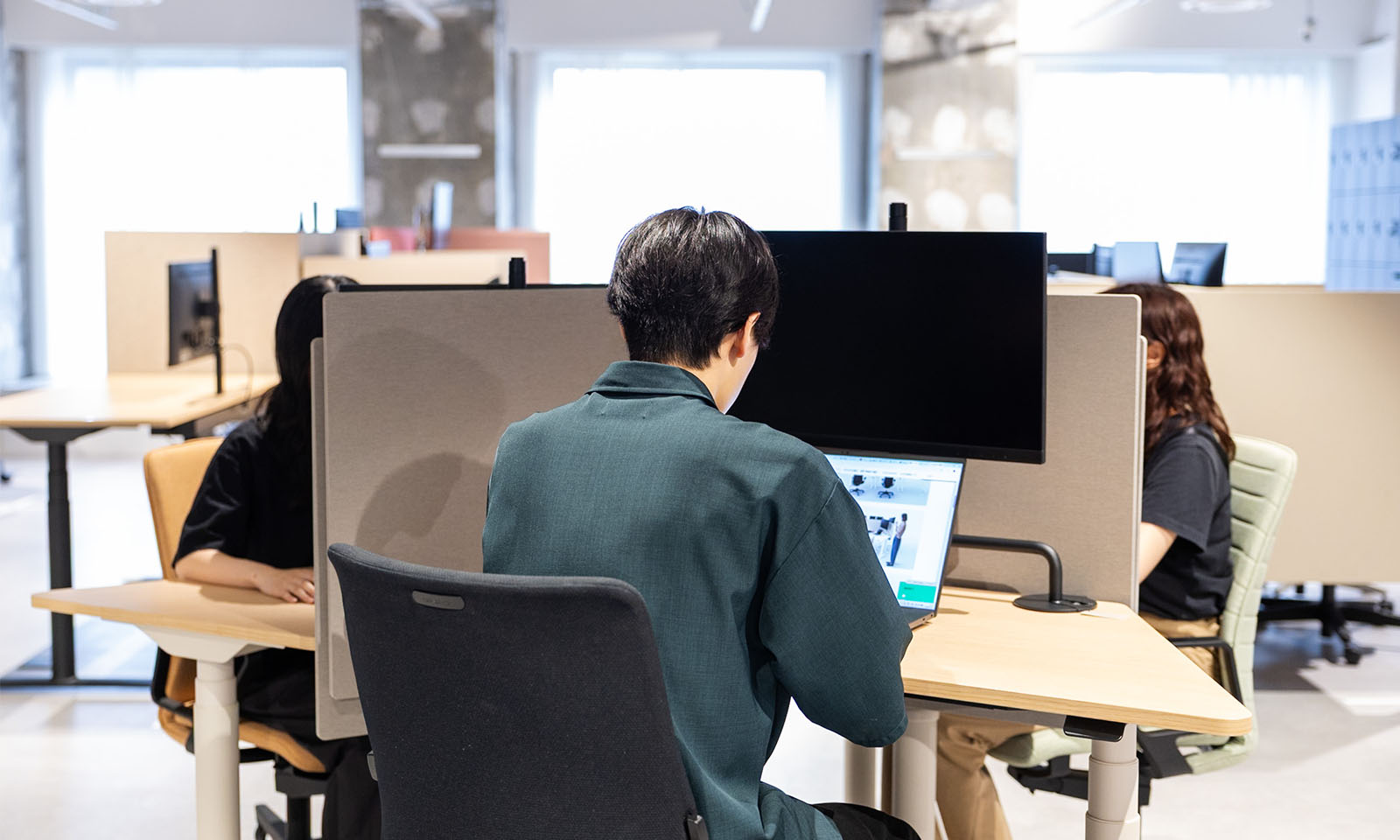 ALTはじまり。画像：「アセンド」を３台並べた三角形のレイアウトで、それぞれの席で作業を行っている。適度に籠れる高さのパネルのおかげで３人座っていても集中できる。画像おわり。ALTおわり。