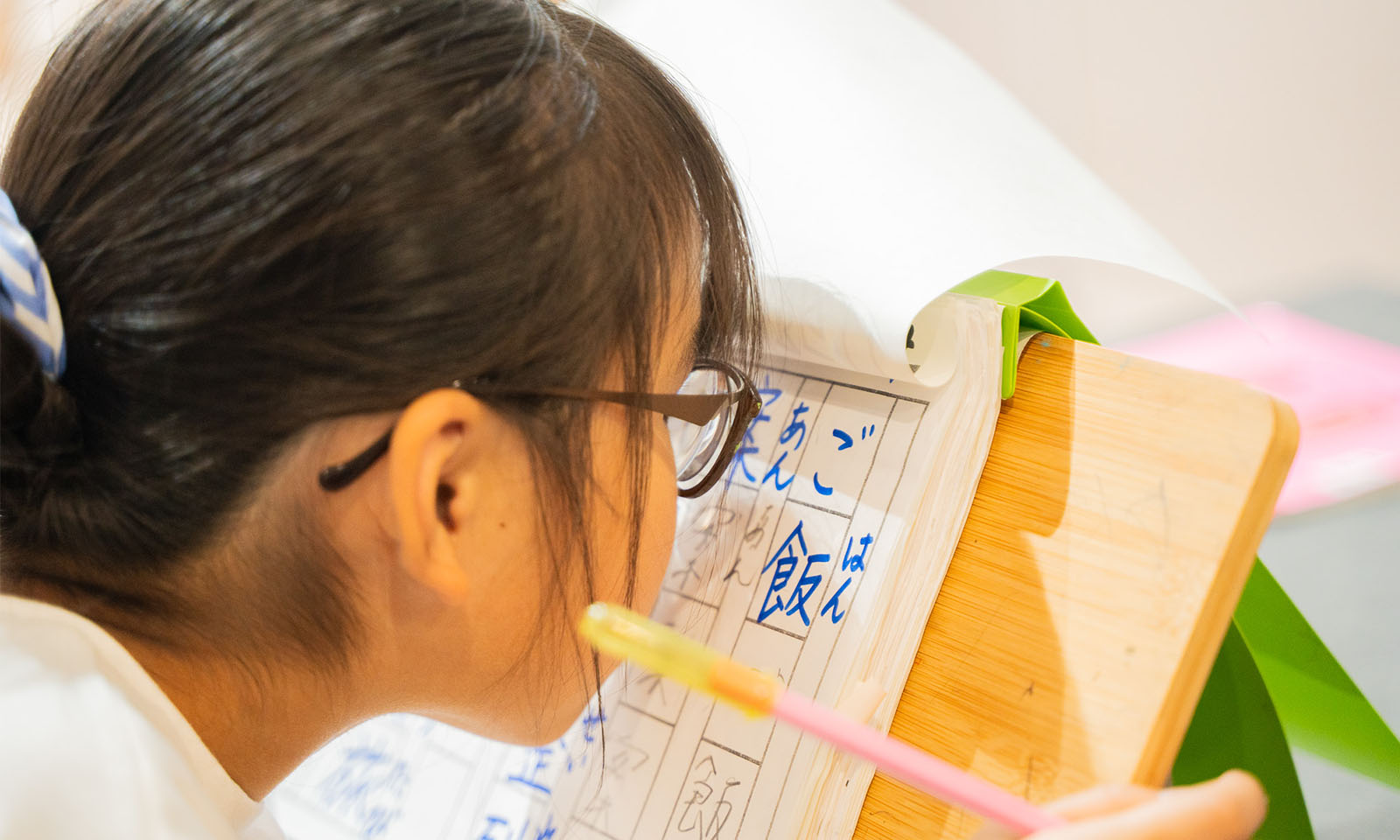 ALTはじまり。ピアノの譜面を置く台のようなツールに漢字ドリルを置いている。こうすることで、姿勢が良いまま、顔を近づけて漢字をじっくり見ることができるようになっている。かのんちゃんは今「ご飯」の「飯」の漢字を練習中。ALTおわり。